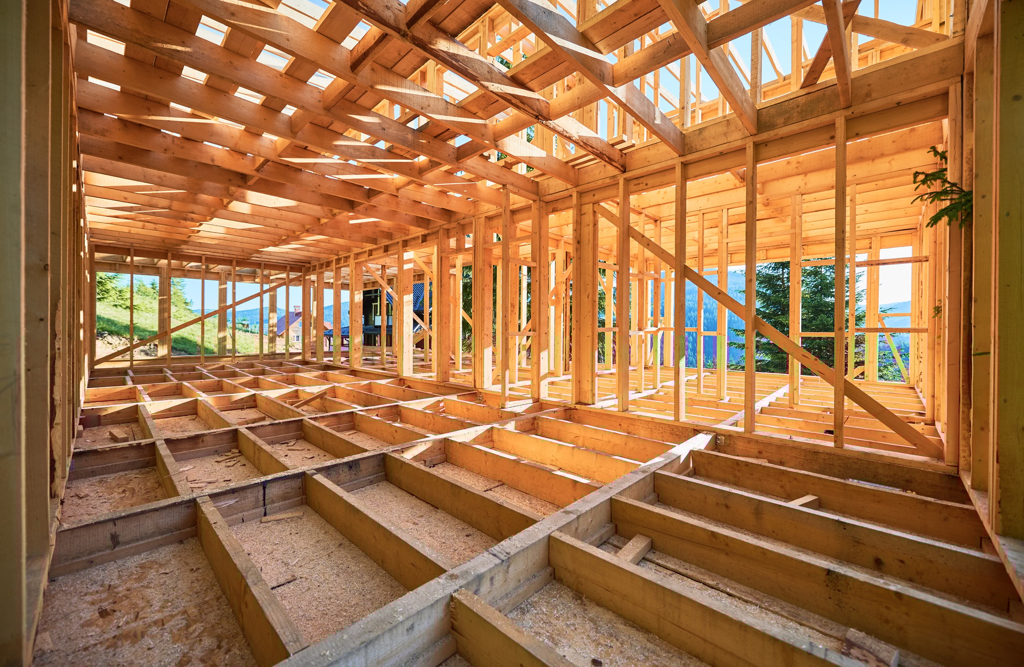 Wooden frame house under construction near forest.